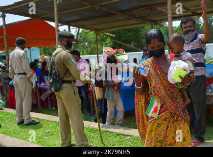 Inde / Tripura / Agartala - les travailleurs migrants et les membres de la famille font la queue pour montrer leurs papiers et sont contrôlés par un thermomètre infrarouge devant une station à bord de l'Express Shramik, à destination de l'État indien de Bihar, Au cours d'un confinement national imposé par le gouvernement comme mesure préventive contre la COVID-19, à la frontière de Joypur, à cinq kilomètres d'Agartala. Capitale de l'État de Tripura, au nord-est de l'Inde. Banque D'Images