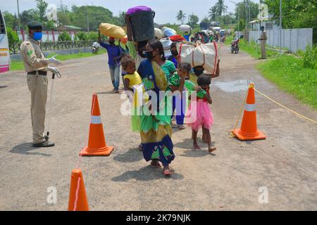 Inde / Tripura / Agartala - les travailleurs migrants et les membres de la famille font la queue pour montrer leurs papiers et sont contrôlés par un thermomètre infrarouge devant une station à bord de l'Express Shramik, à destination de l'État indien de Bihar, Au cours d'un confinement national imposé par le gouvernement comme mesure préventive contre la COVID-19, à la frontière de Joypur, à cinq kilomètres d'Agartala. Capitale de l'État de Tripura, au nord-est de l'Inde. Banque D'Images