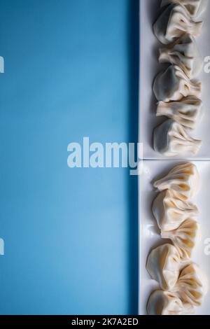 les boulettes traditionnelles de khinkali géorgiennes se flatlay avec espace d'imitation, fond bleu Banque D'Images