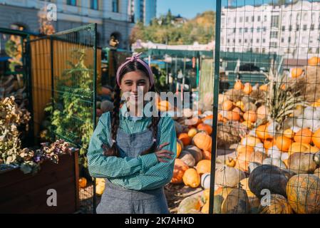 Une femme agricole vend la récolte de citrouille d'automne sur le marché Banque D'Images