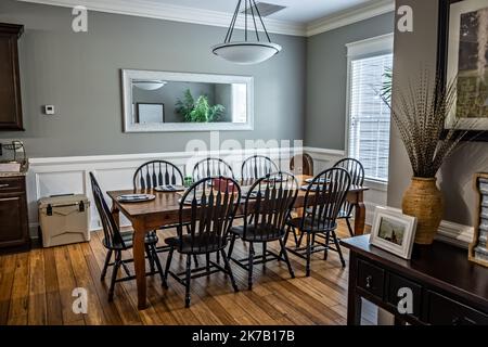 Cette grande salle à manger est dotée d''un tabel de ferme simple et de chaises, d''une fenêtre, d''un miroir et de parquet Banque D'Images