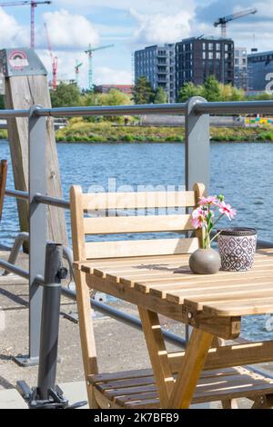 Siège confortable et ensoleillé à une table de café en bois sur la rive de Baakenhafen à Hambourg. Vue sur le nouveau Baakenpark dans la Hafencity. Banque D'Images