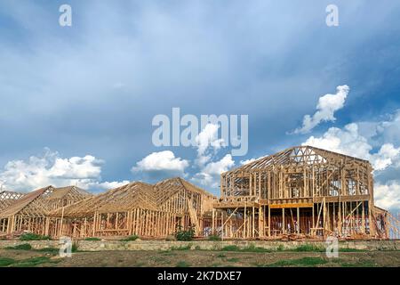 Cadre en bois site de construction résidentielle avec beau ciel bleu sur fond. Grande maison en construction en phase de cadrage. Banque D'Images