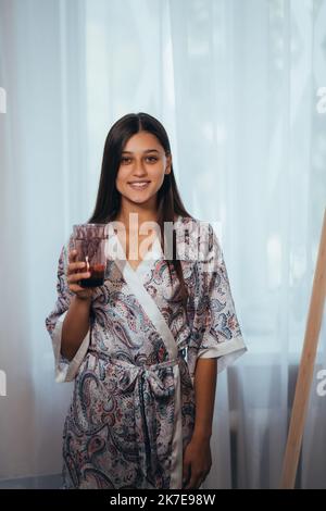 Femme debout à l'intérieur tenant de verre boire de l'eau Banque D'Images