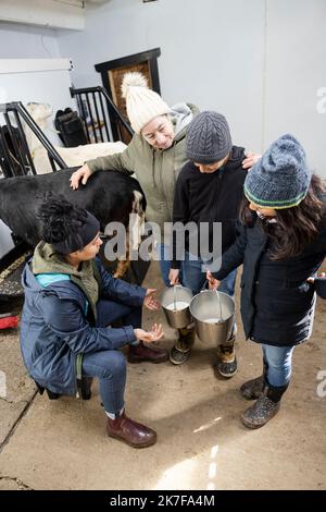 Famille avec des seaux de traite des chèvres dans la grange