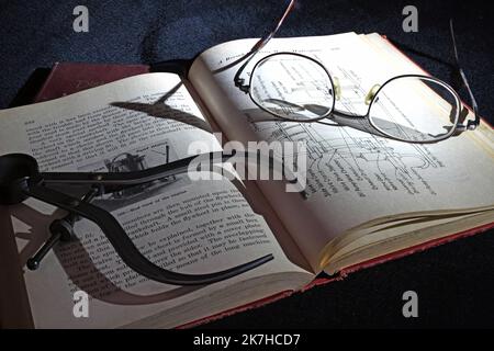 Livre de génie antique avec pieds à coulisse dans la lumière tamisée Banque D'Images