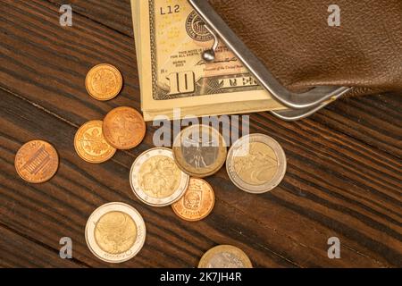 Billets en dollars, pièces en euros et portefeuille vintage en cuir marron sur une surface en bois. Gros plan, mise au point sélective. Banque D'Images