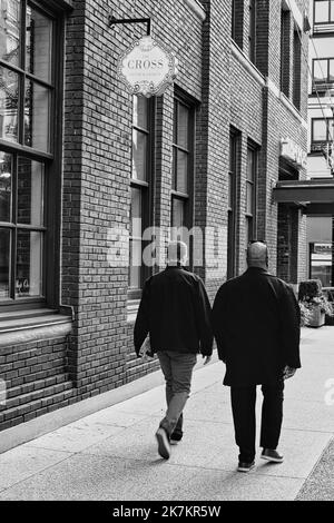 Deux personnes marchant dans la rue au centre-ville de Vancouver, C.-B. Canada. Deux hommes d'affaires en costume marchant à l'extérieur dans la ville urbaine. Photo de voyage, vue sur la rue, sélection Banque D'Images