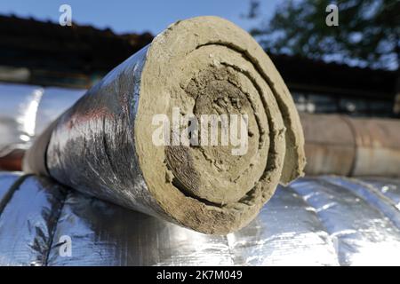 Détails de faible profondeur de champ (mise au point sélective) avec laine de verre industrielle utilisée pour isoler thermique un pipeline métallique d'eau chaude. Banque D'Images