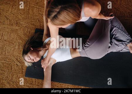 Exercices de yoga. Un entraîneur personnel enseigne à une femme des cours de yoga dans la salle de gym Banque D'Images