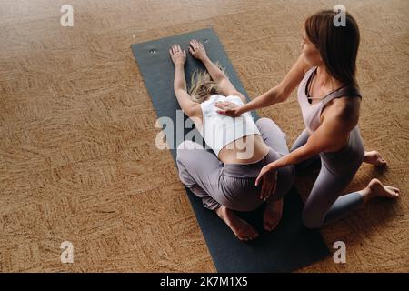 Exercices de yoga. Un entraîneur personnel enseigne à une femme des cours de yoga dans la salle de gym Banque D'Images