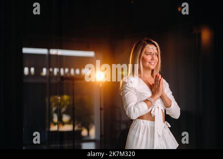 Portrait d'une fille souriante dans une robe blanche avec ses paumes clastées devant elle Banque D'Images