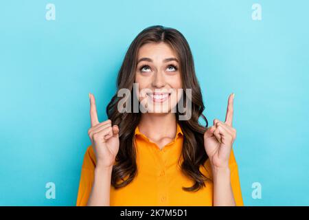 Photo portrait de la jolie jeune femme point chercher l'espace vide habillé élégant jaune élégant décontracté ensemble isolé sur fond bleu de couleur Banque D'Images