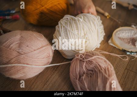 Vue rapprochée d'une boule de fils à tricoter de couleur vive à la maison sur un plancher en bois. Un passe-temps intéressant. Pelotes de ficelle en coton confortables. Excellente image Banque D'Images