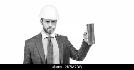 ingénieur en casque avec spatule. renouvellement et réparations. homme d'affaires confiant en costume, espace de copie Banque D'Images