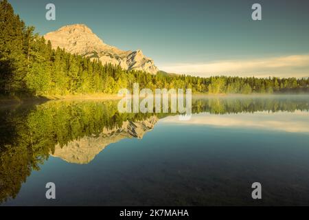 Arbres se reflétant dans Wedge Pond à l'heure d'or, Rocheuses canadiennes, Alberta, Canada Banque D'Images