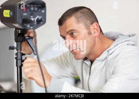 photographe contrôlant la tête d'éclairage stroboscopique du flash studio Banque D'Images
