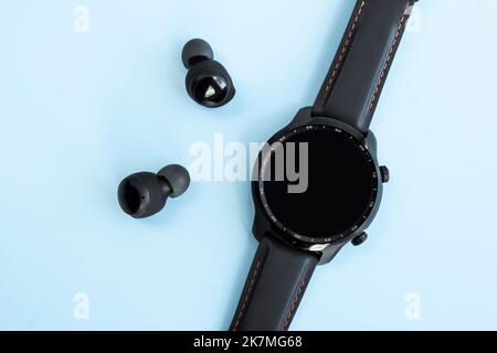 montre intelligente noire et casque sans fil sur fond bleu. Écran vide. Espace de copie. Banque D'Images