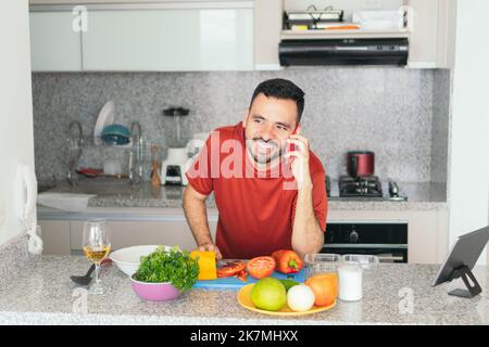 Latin Man parlant sur téléphone portable tout en préparant le petit déjeuner à la maison Banque D'Images