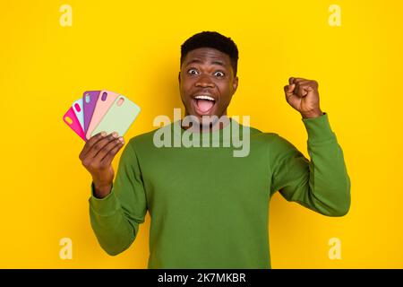 Portrait de beau mode gai gars holidng mobile étuis se réjouissant d'avoir l'amusement isolé sur fond jaune clair de couleur Banque D'Images