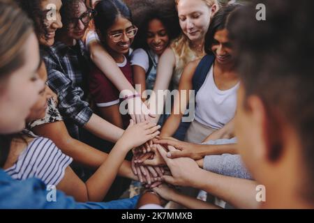 Divers adolescents sourient avec joie tout en mettant les mains ensemble dans un caucus. Groupe de jeunes enfants multiculturels symbolisant l'unité et le travail d'équipe. Banque D'Images