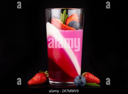 Gelée de fruits avec fraises et bleuets dans un verre sur fond noir, un magnifique dessert. Banque D'Images