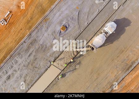 Les travailleurs qui travaillent pendant la construction d'un camion de mélange de béton de trottoir versent du ciment Banque D'Images