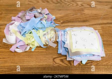 tas de morceaux de tissus de soie découpés avec des motifs de papier fixe préparés pour patchwork sur table en bois Banque D'Images