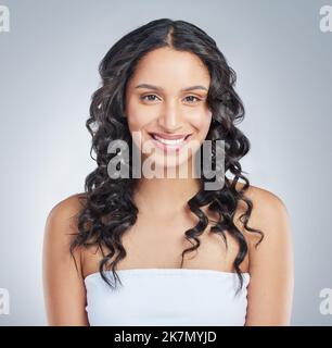 Une sensation de féminité. une jeune femme attrayante debout seule et posant avec des cheveux bouclés dans le studio. Banque D'Images