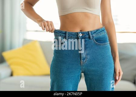 Une dame ajustée qui pose après avoir réussi à porter des jeans à l'intérieur Banque D'Images