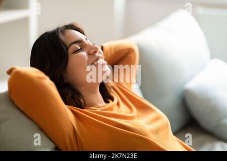 Confort à la maison. Portrait de la jeune femme arabe souriante penchée sur le canapé Banque D'Images