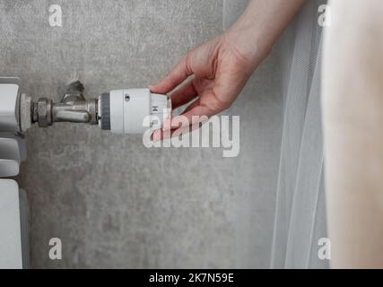 Femme réglant la température sur le radiateur de chauffage. économie et préservation de la chaleur dans la pièce Banque D'Images