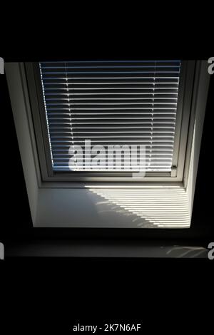 Un portrait d'une fenêtre de toit en velours avec un jalousie à moitié ouvert pour garder le soleil et la chaleur à l'extérieur ou pour empêcher la lumière d'entrer dans la pièce dans la Mo Banque D'Images