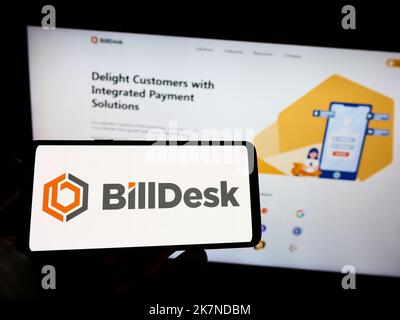 Personne tenant le téléphone portable avec le logo de la société IndiaIdeas.com Limited (BillDesk) sur l'écran en face de la page Web d'affaires. Mise au point sur l'affichage du téléphone. Banque D'Images