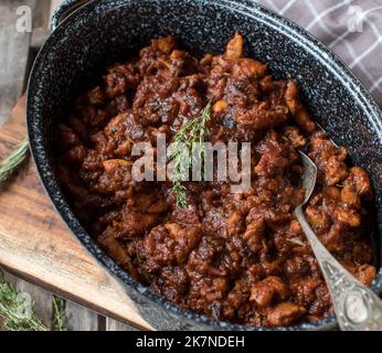 Ragoût italien avec viande de poulet, tomates, ail, herbes et vin rouge dans une casserole rustique Banque D'Images