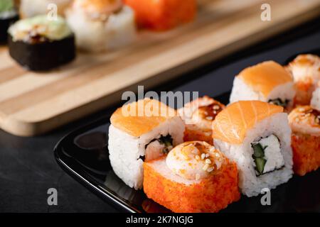 Ensemble de petits pains à sushis de Philadelphie sur une assiette noire. Il sert de la cuisine japonaise au restaurant. Plat asiatique populaire de riz et de saumon. Rouleaux d'uramaki. Banque D'Images