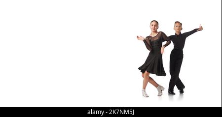 Deux enfants, jeune fille et garçon en costumes de scène noire dansant la danse de salle de bal isolée sur fond blanc. Art, danse sportive, musique, étudier Banque D'Images