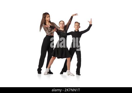 Cours de danse avec entraîneur personnel. Deux enfants, une fille et un garçon d'âge scolaire en costumes de scène noire étudiant à danser isolés sur fond blanc. Art Banque D'Images