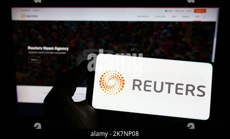 Personne tenant un smartphone avec le logo de l'agence de presse Reuters sur l'écran devant le site Web. Mise au point sur l'affichage du téléphone. Banque D'Images