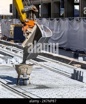 Pelle hydraulique remplissant le sable dans une brouette sur un chantier de construction Banque D'Images