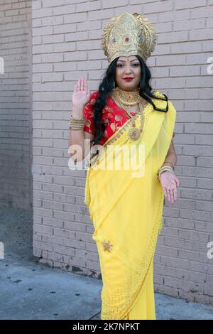 Une jolie femme hindoue portant une couronne et un sari jaune et portant la déesse Lakshmi. Au Diwali 2022 à Queens, New York. Banque D'Images