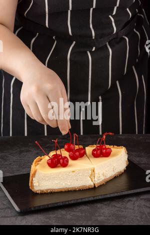 Le chef décorera un cheesecake classique avec des baies de cerise sur un fond sombre Banque D'Images