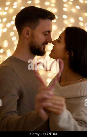 Portrait de famille aimant des vacances embrassant et montrant le coeur de bonbon avec des lumières de bokeh en arrière-plan.Concentrez-vous sur le couple Banque D'Images