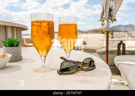 Deux verres avec bière et lunettes de soleil sur une table sur un toit-terrasse, restaurant, Espagne. Banque D'Images