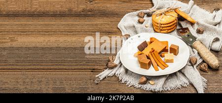 Brunost norvégien avec biscuits et noix. Nourriture saine et alimentation, ingrédient biologique pour le petit déjeuner. Fromage brun scandinave traditionnel, dos en bois Banque D'Images