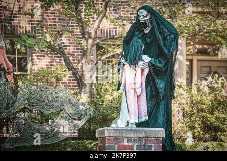 Créature maléfique morte en robe se préparant à dévorer la petite fille de nuit ghoulish Halloween décoration à l'extérieur en face de la maison Banque D'Images