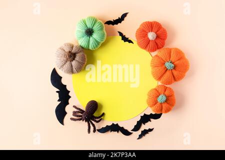 Composition de chauves-souris noires, araignée tricotée, citrouilles tricotées orange et vertes avec un endroit rond jaune pour le texte. Concept Halloween. Banque D'Images