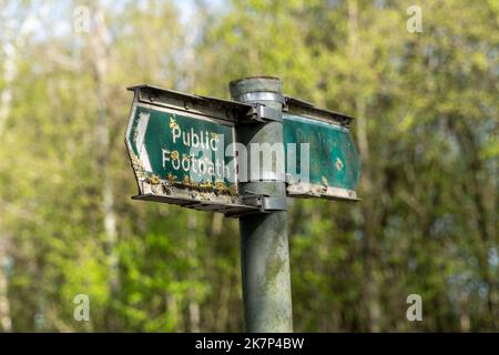 Vieux panneau vert de sentier public avec de la mousse et des litschen qui poussent Banque D'Images