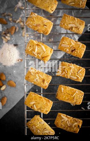 Petits gâteaux faits maison fraîchement cuits sur la grille du four sur fond sombre plat Banque D'Images