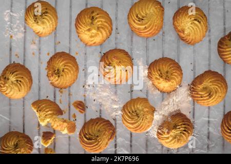 Petits gâteaux faits maison fraîchement cuits sur la grille du four sur fond sombre plat Banque D'Images